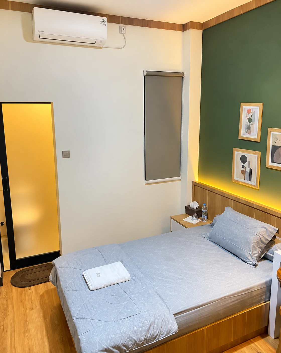 Kamar dengan tempat tidur, AC, dinding hijau, dan pencahayaan hangat